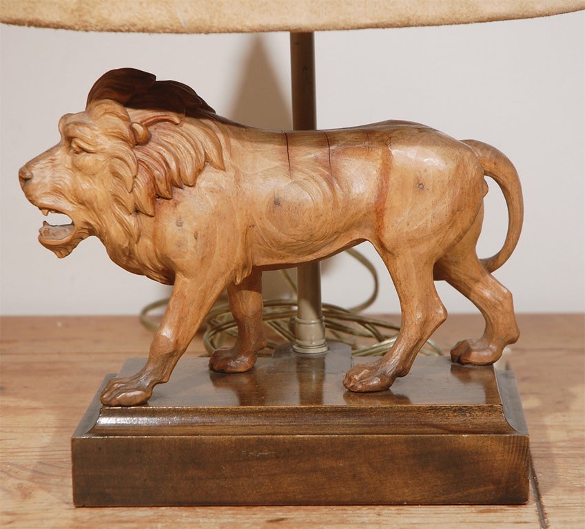 Old wood carved lion lamp with a beige suede oval shade. This is a well carved lion mounted on a carved wood block, with the French mounting up the back topped by the original oval beige<br />
suede shade. Very handsome lamp, unusual, old, and in