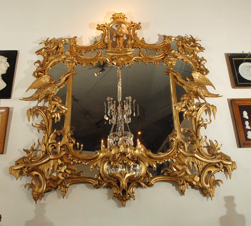 a mid-Georgian giltwood chimney glass or overmantle mirror, interpreted from a design by Chippendale, rococo volutes terminate in a crested pavilion with a pair of robust Phoenix birds anchoring its width, rock piles and stalactites add to the