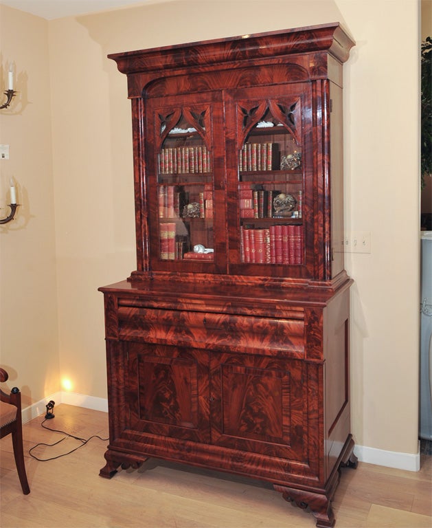 A Fine c Highly Figured Mahogany Desk and Bookcase, attributed to J. & J. W. Meeks, New York, with ogee cornice, arched recessed frieze, Gothicized glazed doors with pierced brackets and flanked flanked by carved columnar supports, the base with an
