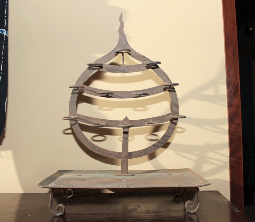 Japanese forged iron votive candle stand in the form of a hoju no tama.  The tear drop-like hoju no tama, or jewel of wish fulfillment, with twelve Iron rings to hold small candles or oil dishes.  The hoju no tama is thought to grant wishes by