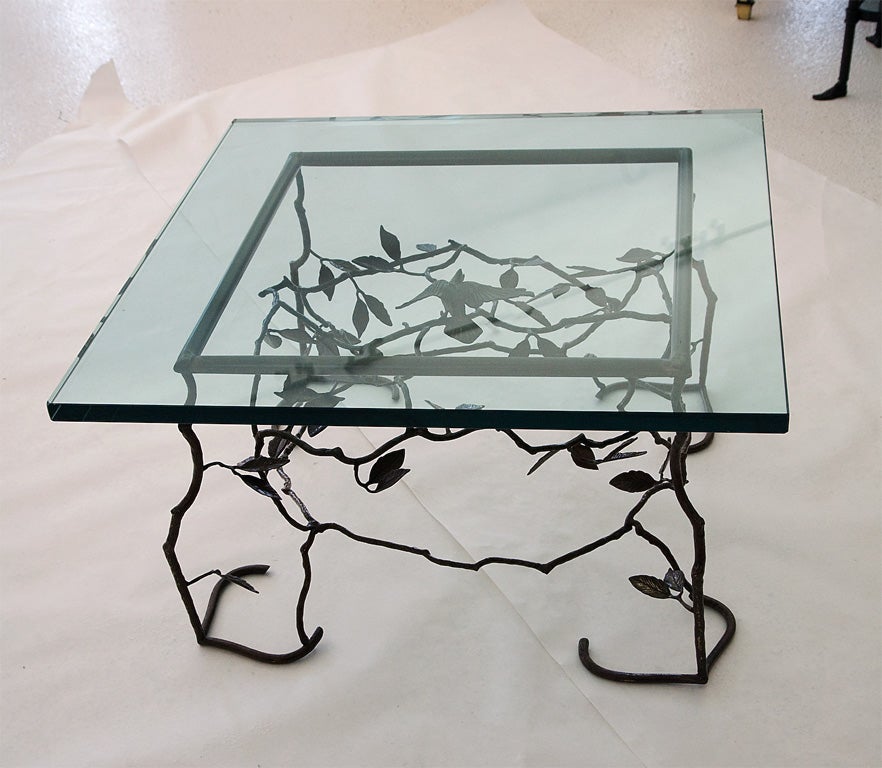 Elegant glass top table with patinated brass base of twigs, and a bird.