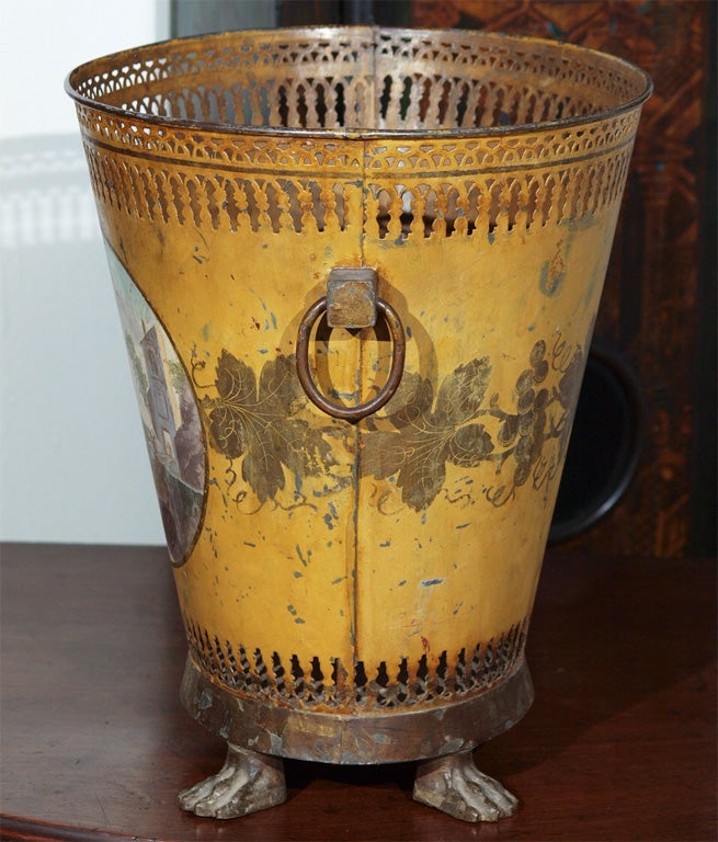 Exceptional Tole peinte jardeinere with original paint having a central scenic medallion and a garland of gilt leaves on a gold ground. this is on a pierced oval bucket with two ring handles and paw feet.
