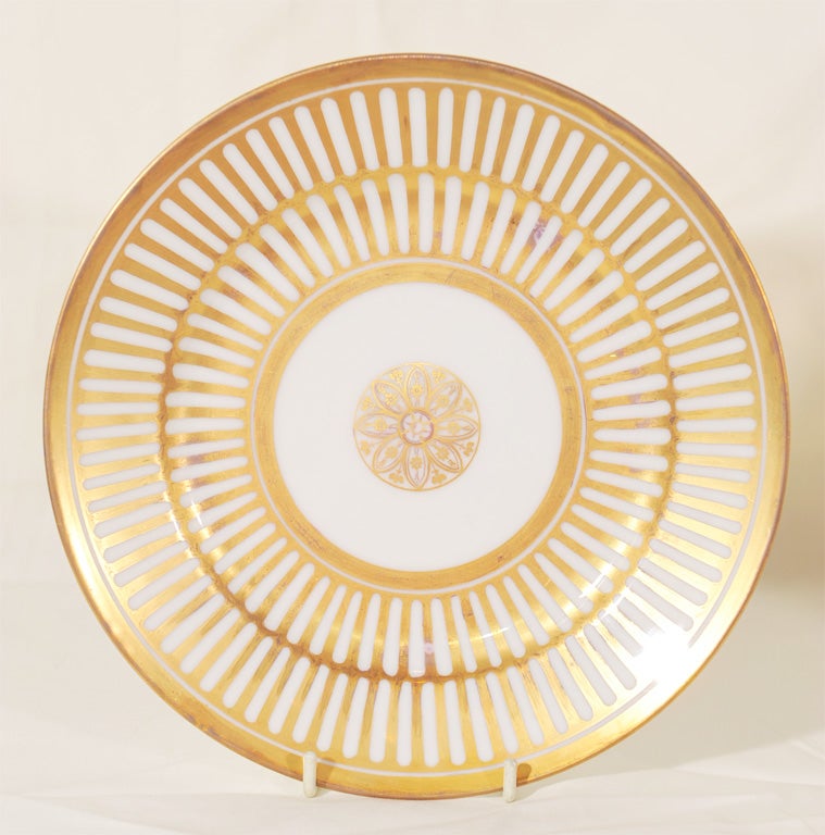 A Dozen White and Gilt early 19th century French dishes made by and with the mark of the Schoelcher factory. Each plate with a gilded central medallion surrounded by radiating lines of gilt. The contrasting white and gold lines create a striking