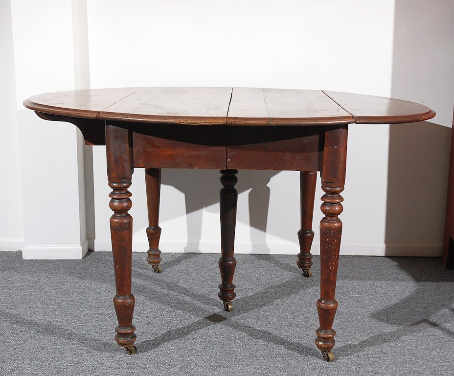 WONDERFUL 19THC WALNUT DROP LEAF TABLE W/ORIGINAL BRASS CASTERS. WONDERFUL WORN PATINA ON THE TOP OF THE TABLE. NICE ORIGINAL SURFACE ON THE LEGS AND BODY OF THE TABLE.