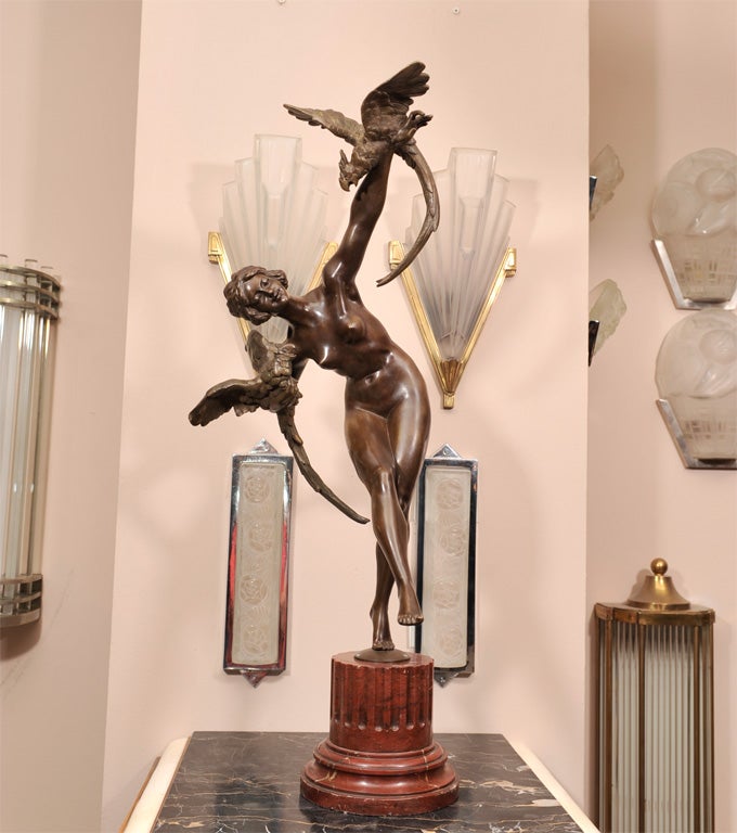 "Dancer with Parrots” (or “Beside the Missouri”),a French Art Deco bronze sculpture by Claire Jeanne Roberte Colinet (Belgian, 1880-1950), from circa 1918. Brown patinated bronze raised on a stepped red-brown marble base. Signed on the base.