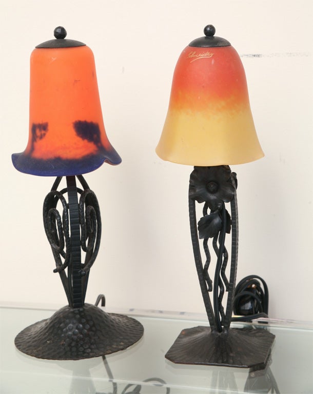 This pair of small french art deco glass and wrought iron lamps were purchased in Paris over 25 years ago. The wonderful French art deco table top lamps are fashioned in pounded wrought iron with colored glass shades. One is signed Schneider as is