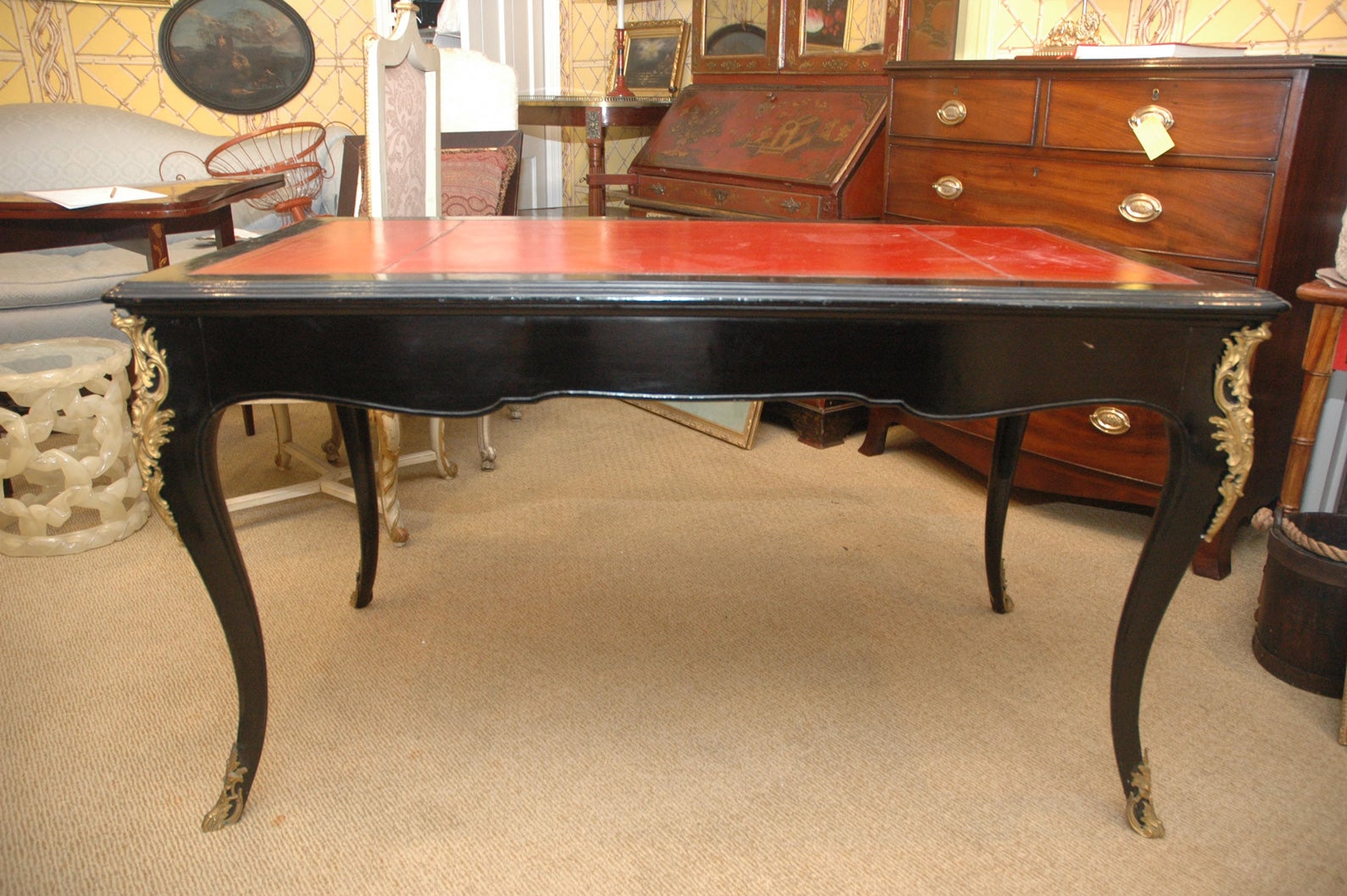 French 19th Century Regency style ebonized bureau plat having ormolu angles on cabriole legs ending in sabots. Original red leather top trimmed with gold tooling.  Two frontal drawers extend to back of the bureau plat.