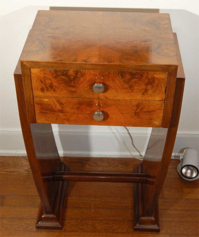 A handsome Art Deco period burl walnut side table from France c. 1930. The rectangular section that contains the two drawers is enclosed by the pair of inward curving vertical supports that each stand on a moulded plinth base. They in turn are