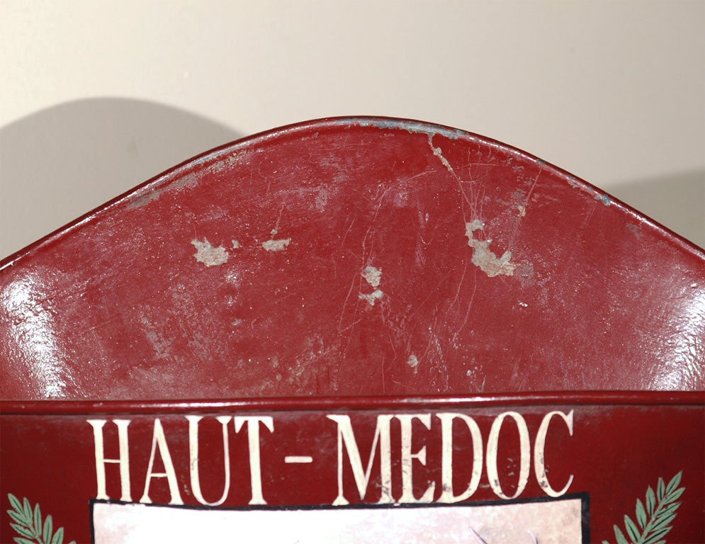 Tin grape hod of the type used by grape pickers in France.  This one is painted red and decorated with the coat of arms of Haut-Medoc portraying a noble red stag.