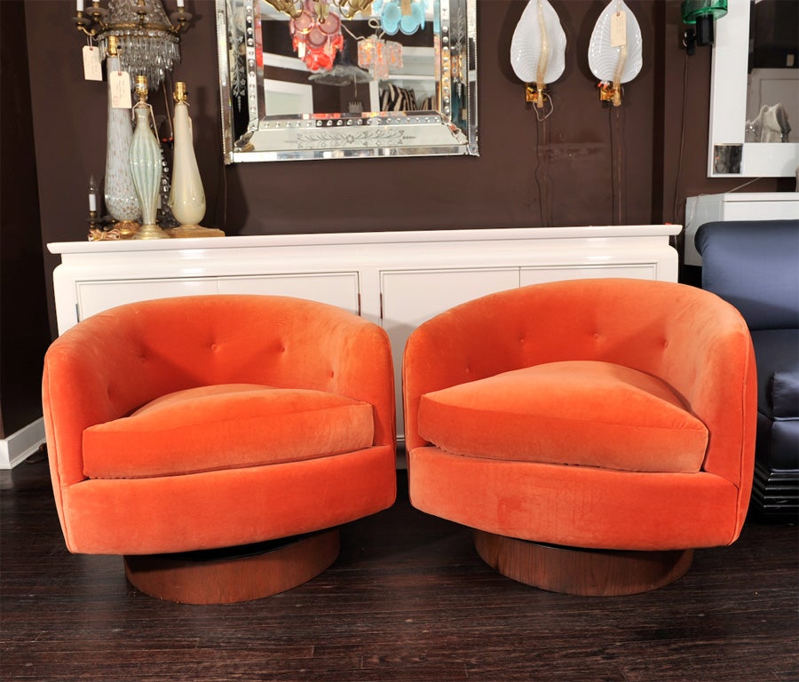 PAIR OF ORANGE MILO BAUGHMAN SWIVEL CHAIRS WITH A WOODEN BASE