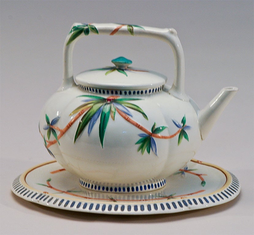 Unusual Wedgwood diminutive teapot with raised molded bamboo decoration. Hand painted polychrome enamel decoration in vibrant coors. The matching trivet completes this wonderful set.