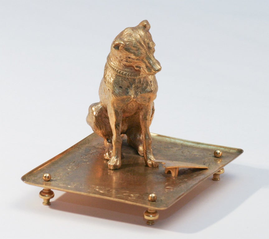 A rare and charming large-scale figural match strike with a well-cast dog eyeing the bootjack striker. His head is hinged and opens to reveal the match holder. The vignette is placed on the 