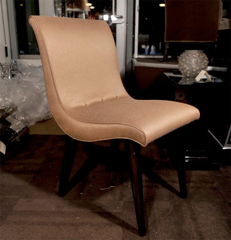 Upholstered dining chairs with<br />
ebonized walnut legs and button <br />
details on the lower backs/seats.<br />
Chairs have sinuous profiles and<br />
tapered legs.