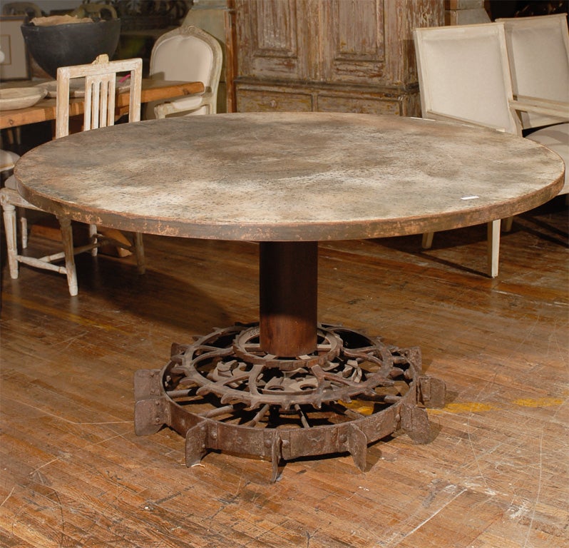 Large round industrial table with a base made from an antique potato picking machine, wood top with metal covering.
