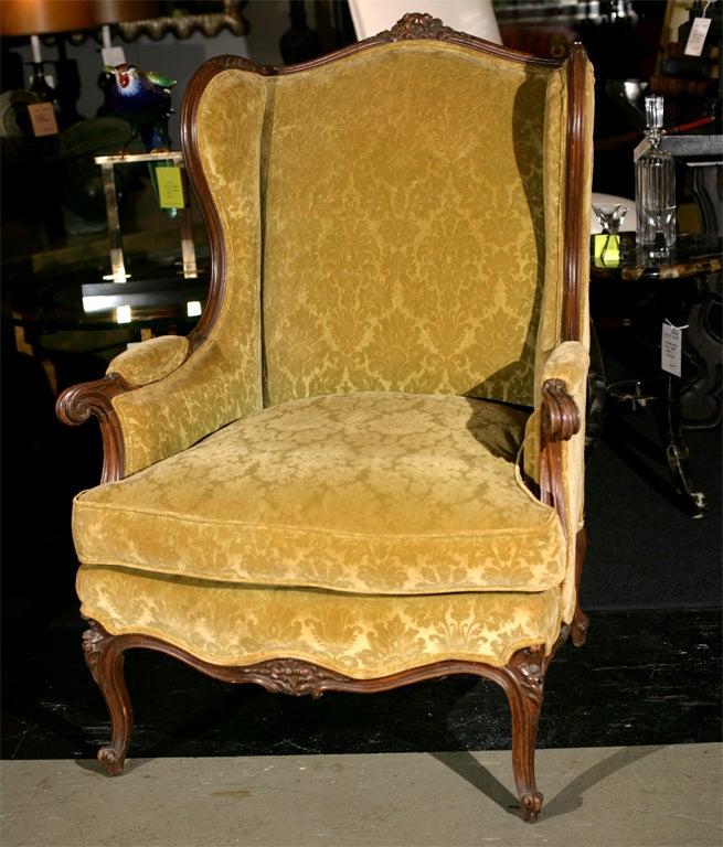 Vintage French style wing chair of traditonal carved walnut. This chair is wonderfully comfortable with a soft down cushion and great proportions.