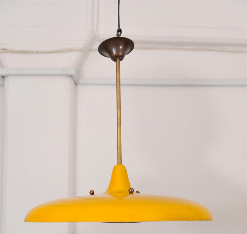 Saucer-shaped yellow enameled metal shade with brass pipe and canopy and brass reflector.