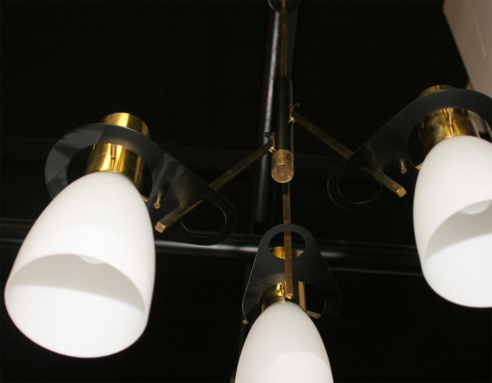 Modernist chandelier made in Italy 1950 by Stilnovo with three white opaline glass shades suspended in a articulated brass frame. Unusual, great quality.
 