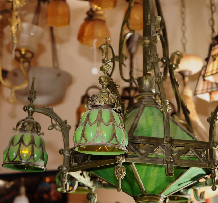 Gothic chandelier with six arms and a center light.  The six side shades consist of emerald green glass blown out through the metal overlay and matching slag glass center.  A high style, impressive piece of workmanship