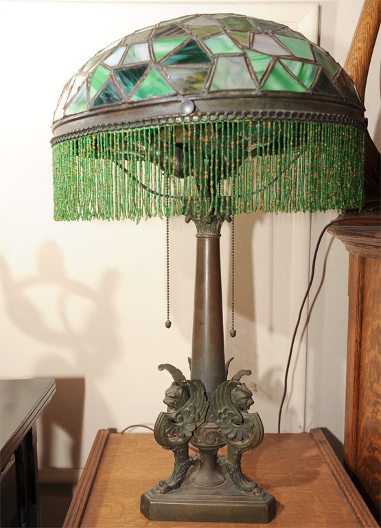 Exotic and high quality table lamp with very unusual shades of green and a fabulous bronze base with winged griffins make this a special package.  Beaded glass fringe makes for a great overall look.