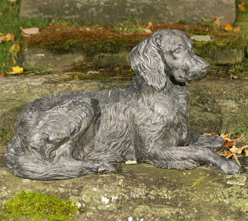 A fine recumbent zinc dog, with head turned slightly to the right and with right front leg extended.<br />
This model is termed the 