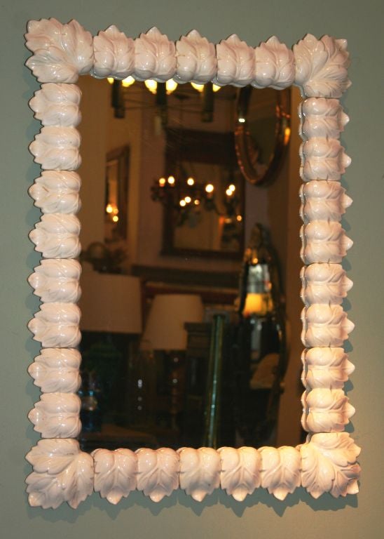 Individual white ceramic leaves frame this mirror.