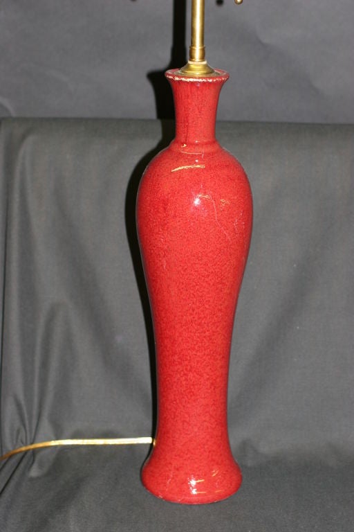 Pair of red ceramic vases with lamp application. The newly wired lamps come with dual, individually controlled sockets and can accommodate up to 100 watts each. Measures: The vases are 16.75