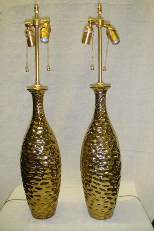 Pair of 1970's Glamorous french gold metallic gouged ceramic lamps.The newly wired lamps come with dual, individually controlled sockets and can accommodate up to 100 watts each. Measures: The vases are 18