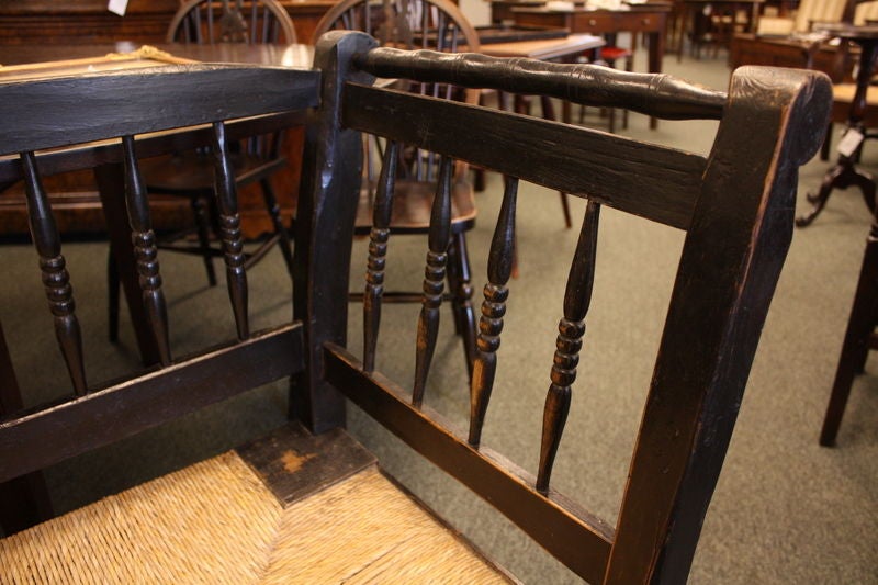An antique rush seat bench from France. The original black paint has nice age to it. Note the spindle back and turned stretchers.<br />
<br />
See similar examples of benches on our website BriggsHouse.com.<br />
<br />
Briggs House, fine