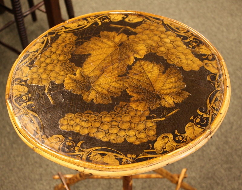 A small round antique English decoupaged bamboo table, decoupaged with grape leaves and grapes. Charming, and useful as a lamp or end table.
 