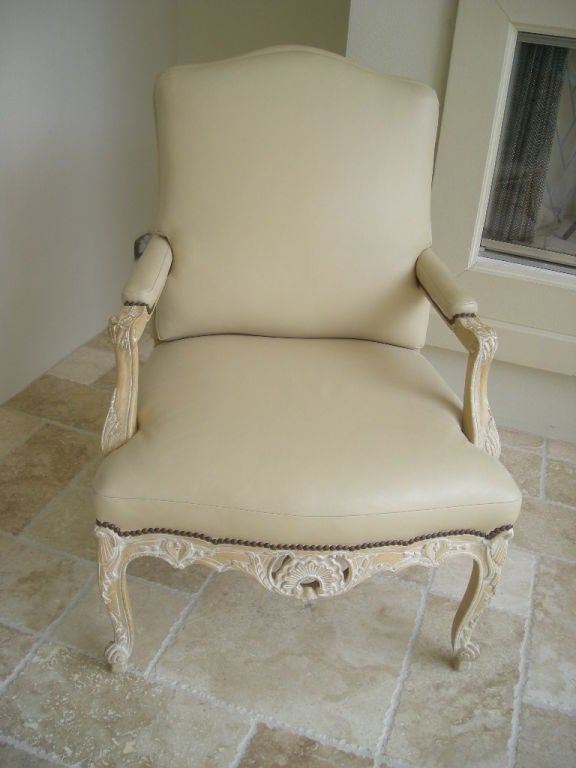 Hand-carved fauteuils upholstered in  cream leather with a moss green & cream silk  striped design fabric finishing the back ; leather is aligned with antique brass nail heads around seat, back rest and arm rests.
