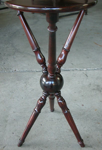 A charming English Edwardian cherrywood tripod croquet table; the shaped circular top with 3 recesses for croquet mallets; raised on 3 turned blauster supports tapering to a central sphere emanating 3 similarly turned legs