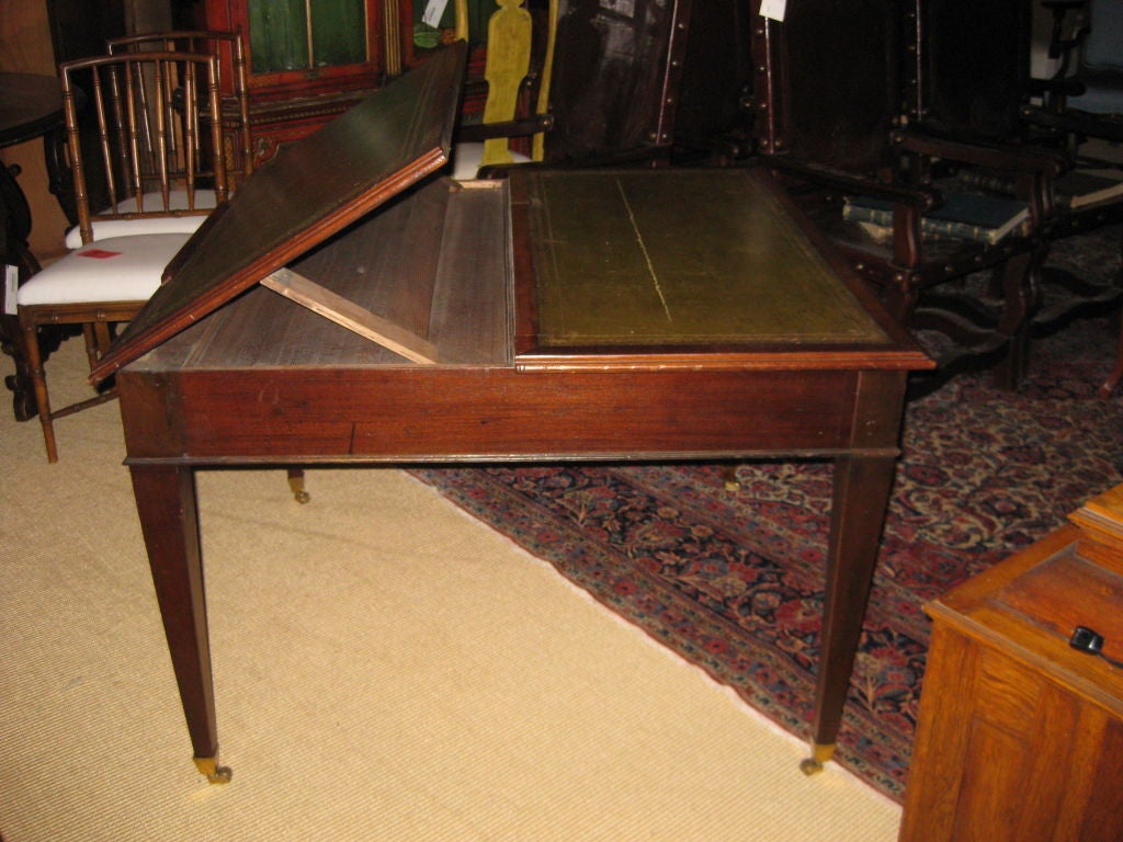Unusual writing and reading table with one side that can be raised to hold a book or for drawing.  This has an embossed leather top and four drawers.