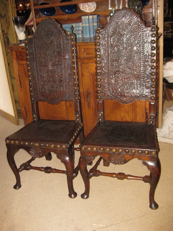 Stunning pair of embossed leather and tac high back chairs with bronze finials and carved shell design