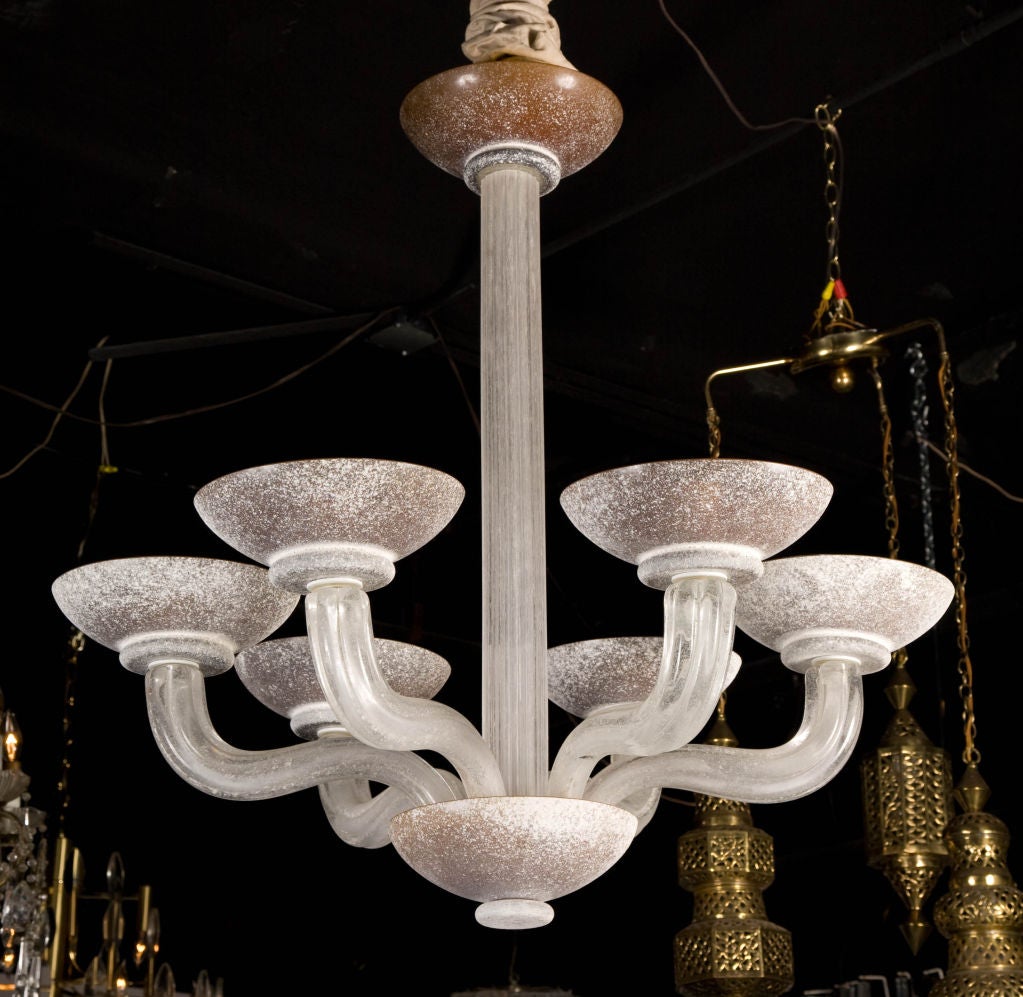 An elegant chandelier with six fluted curved clear glass arms supporting circular amber colored cups, designed by Karl Springer and made by Seguso, Murano Italy. American, circa 1980.