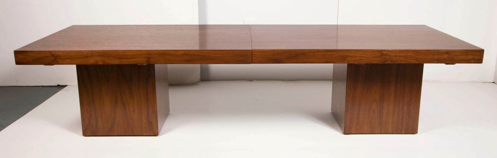 A multifunctional cocktail table with sliding walnut “sleeves” that open to a laminate dry-bar surface. Extends to 96” wide. Top rests on two walnut square pedestal bases. By John Keal for Brown Saltman. American, circa 1950.