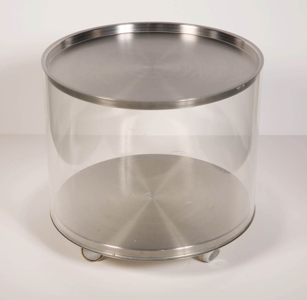 A mod rolling tabouret table in a drum form made of acrylic with removable stainless steel tray top and stainless steel base on four Shepard casters, by Pace. American, circa 1970.