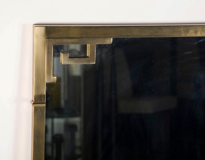 A large mirror finished in antique brass in a rectangular form with Chinoiserie brackets, by Mastercraft. American, circa 1970.