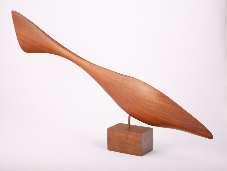 A delicately carved walnut fish sculpture balancing on a rectangular block base by Emilan. American, circa 1950.