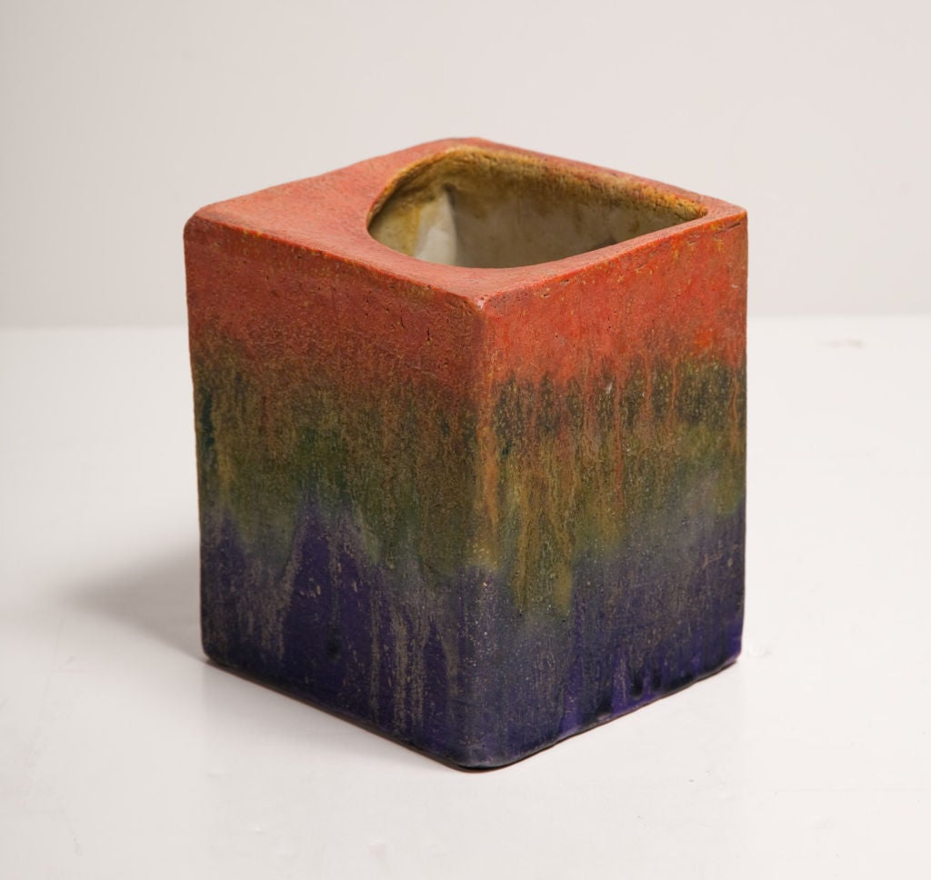 A wonderful ceramic pillow vase in a cube form with a half-moon opening at the top, finished in a matte glaze with layers of red, green, and blue. Signed to the underside. By Fantoni for Raymor. Italy, circa 1950.