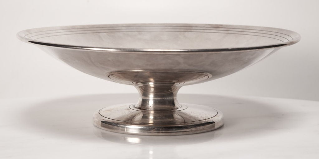 A fine sterling silver compote comprising a shallow bowl with three incised rings to the interior, resting on a squat stem that is supported by a wide circular foot. Incised to the underside of base “Made by Dorlyn Silversmiths”. By Tommi Parzinger