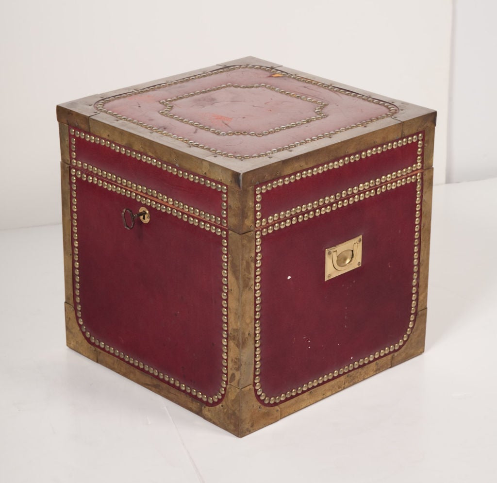 A treasure chest strong box that doubles as an occasional table wrapped in crimson leather with brass corner edges and hobnail studded detailing throughout.  Complete with key, inset metal handles, and mahogany interior. Italian, circa 1950.