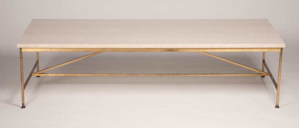 A Minimalist rectangular cocktail table comprising a beautiful travertine stone top resting on a square tube brass base with a satin finish, model. no. 8715. The base has a double cross brace-stretcher. By Paul McCobb for Calvin Furniture, U.S.A.,