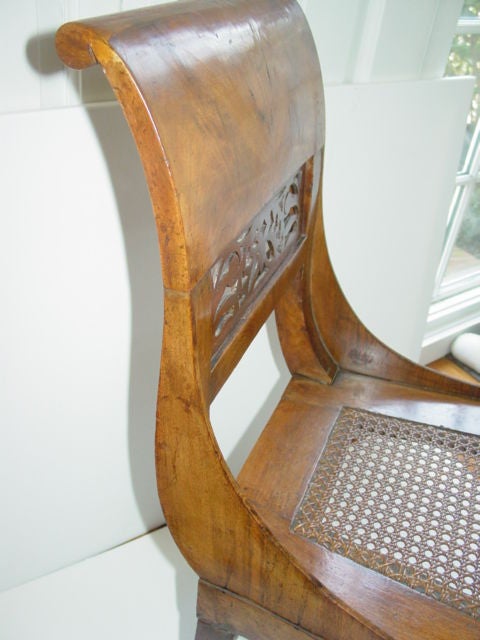 A fine antique Biedermier Walnut wood side chair. With sabre legs, decorative pierced slats and rolled back top frame. Caned seat and the finest craftsmanship.