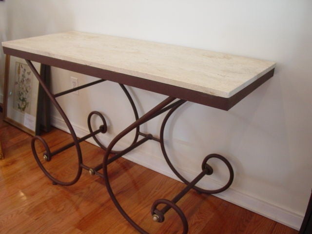 A very useful travertine and scrolled iron serving table/console table. The travertine is oatmeal in color, the iron base is rust in color.