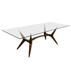 A sculptural exotic wood and bronze dining table with glass top