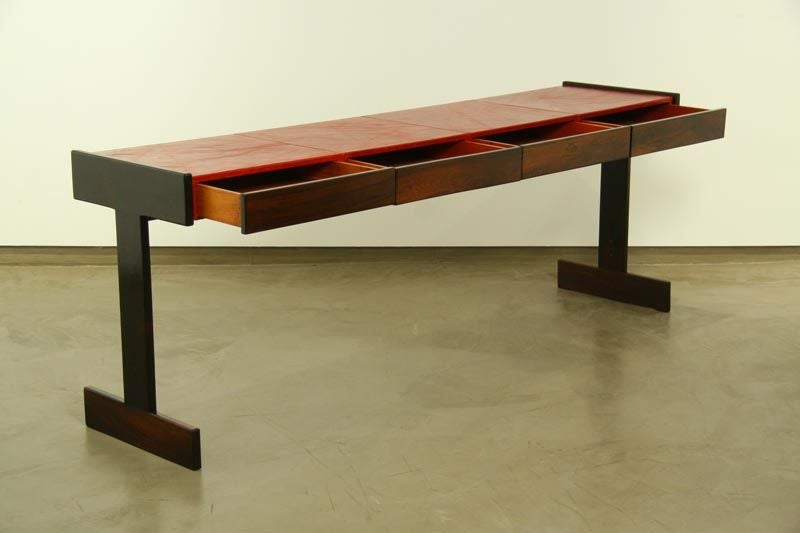 A four drawer console table in Rosewood and red leather