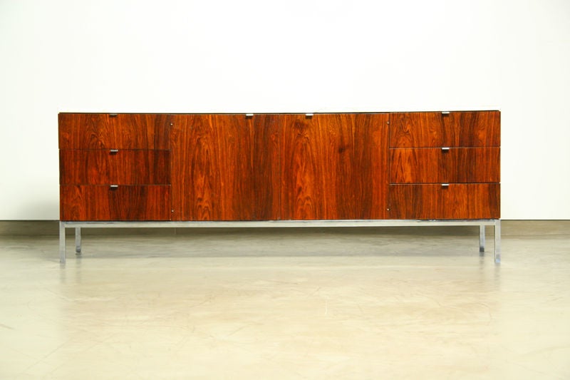 A rosewood cabinet composed of six drawers and two doors, all with chrome pulls.  A chrome base and marble top complete the piece.  Note that although the back is finished, there are already two holes for media cables. There is also a hole for