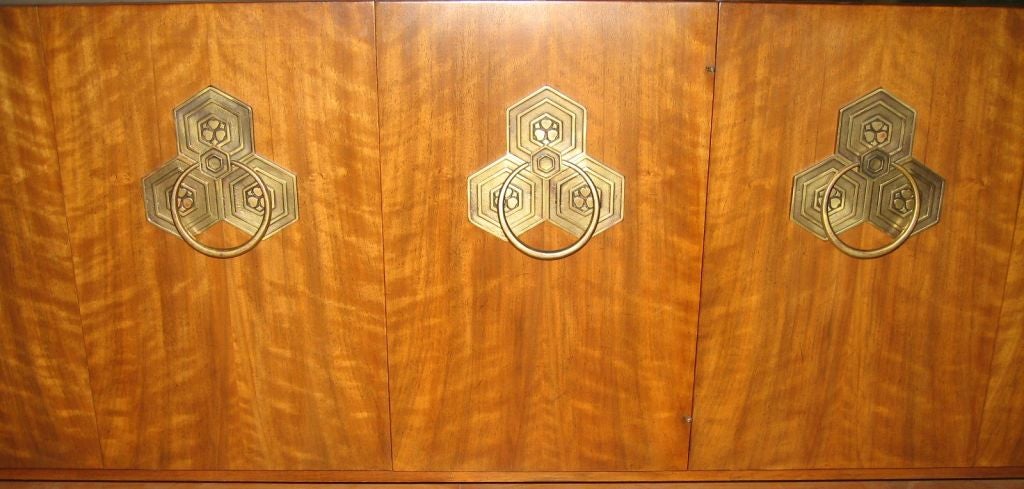Superb example by designer Bert England, this credenza was made for Widdicomb's Orientations Collection in 1965, and is rendered in persian pearwood veneers over oak and mahogany solids. 

Fabulous clustered hexagonal hardware with ring pulls