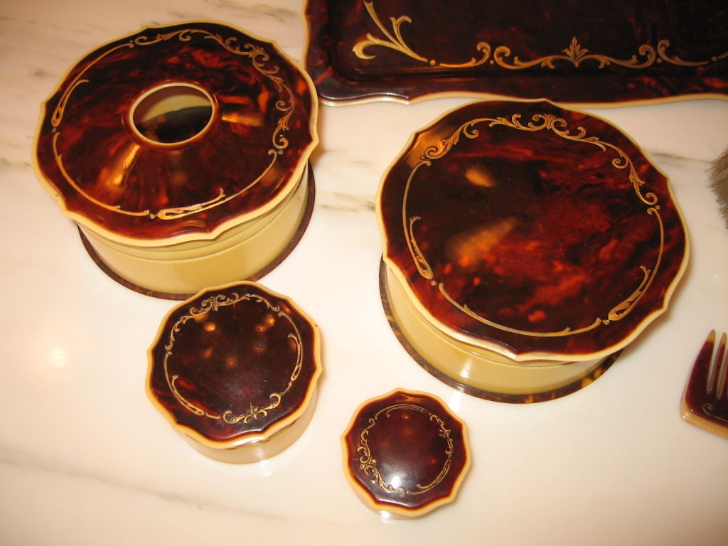 Superb late 30's tortoise and celluloid dresser/vanity set in pristine condition. Luminous tortoise finish bakelite and celluloid bodied pieces, comprised of a tray, hair receiver, covered powder box, rouge box, and cream box, brush and comb.