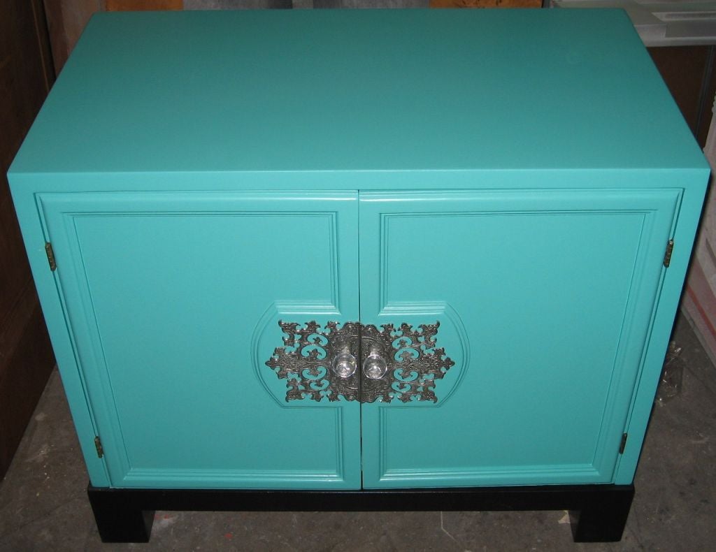 Superb pair of Asian style night stands or end tables dating to the 1950's. Recently refinished in a satin turquoise lacquer with satin black block form bases, this pair retain their original nickel and acrylic hardware. Two doors open to reveal